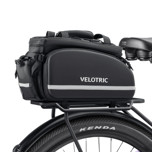 A black Velotric rack top bag with reflective accents, attached to a bicycle rear rack.