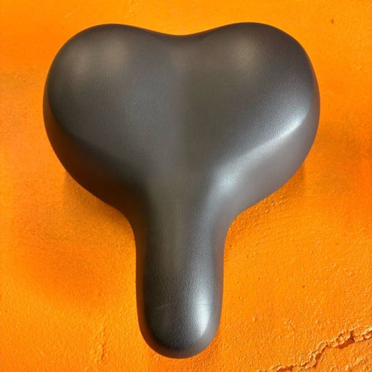 Black city-style eBike seat with ergonomic design, slightly curved shape, and visible stitching, photographed on a white background.